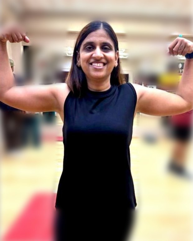 Madhuri Bhangariya smiling and flexing her arms in a gym